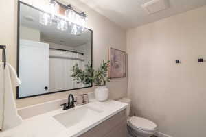 Bathroom featuring a textured ceiling, vanity, and curtained shower