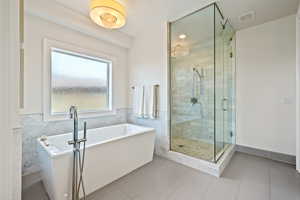 Full bathroom featuring a freestanding bath, a stall shower, tile patterned floors, wainscoting, and tile walls