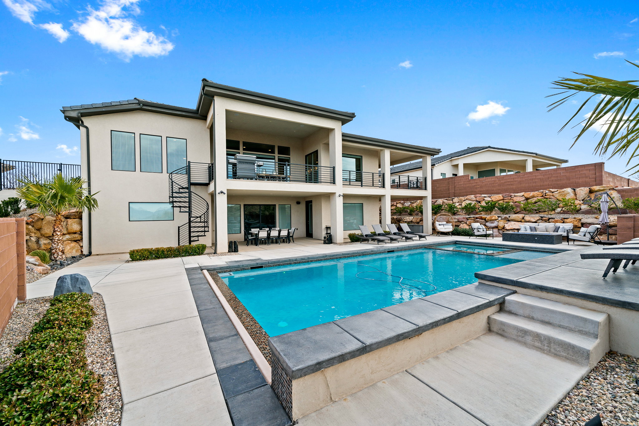 Rear view of house featuring stairway, stucco siding, a balcony, and a patio area