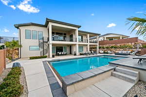 Rear view of house featuring stairway, stucco siding, a balcony, and a patio area