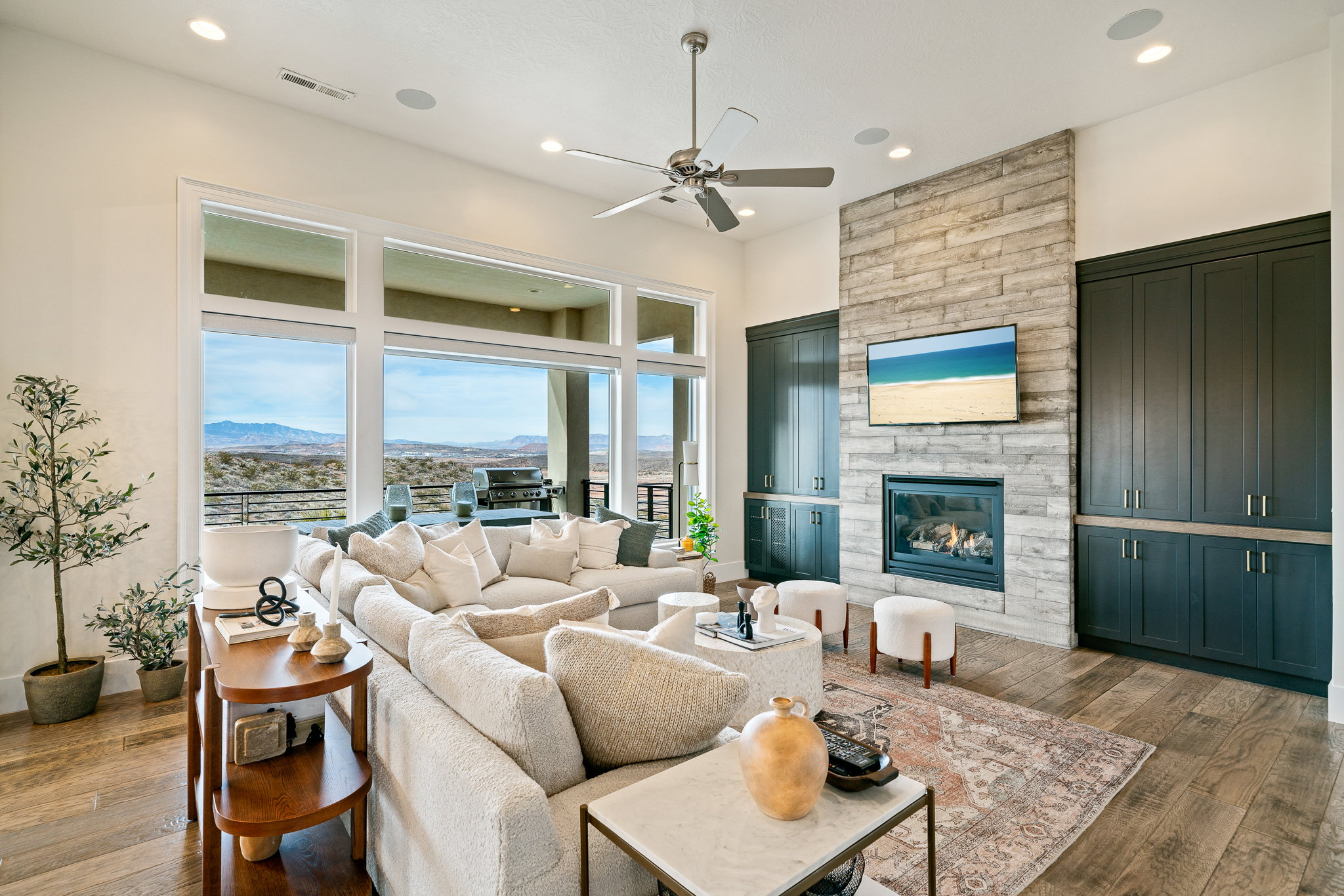 Living area with hardwood / wood-style floors, a ceiling fan, recessed lighting, and a stone fireplace