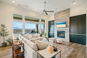 Living area with hardwood / wood-style floors, a ceiling fan, recessed lighting, and a stone fireplace