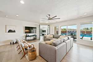 Living area with recessed lighting, light wood-style flooring, ceiling fan, and a textured ceiling