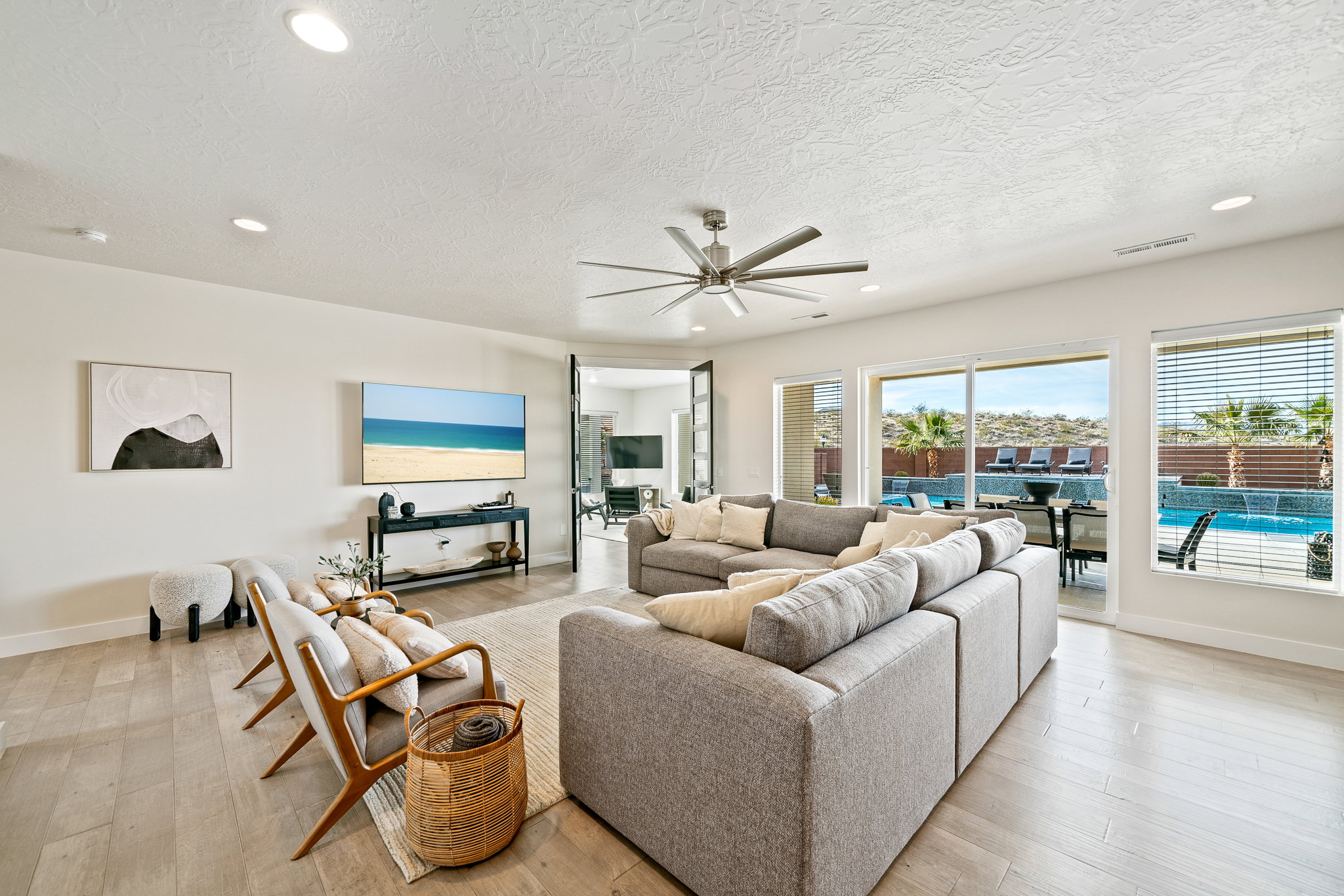 Living area with a ceiling fan, recessed lighting, light wood-style flooring, and a textured ceiling