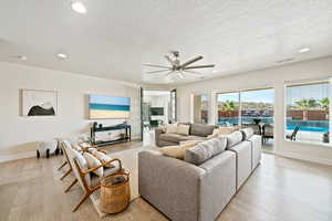 Living area with a ceiling fan, recessed lighting, light wood-style flooring, and a textured ceiling