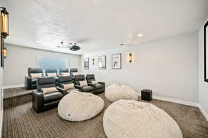 Home theater room featuring carpet flooring, a textured ceiling, and recessed lighting