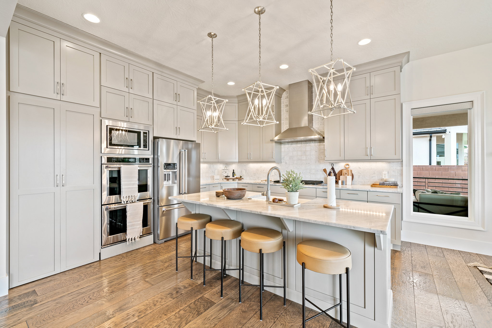 Kitchen featuring light wood-type flooring, stainless steel appliances, wall chimney exhaust hood, a breakfast bar, and a chandelier