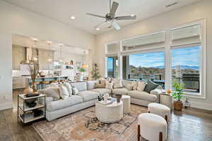 Living room with dark wood-style floors, a ceiling fan, recessed lighting, a chandelier, and a mountain view