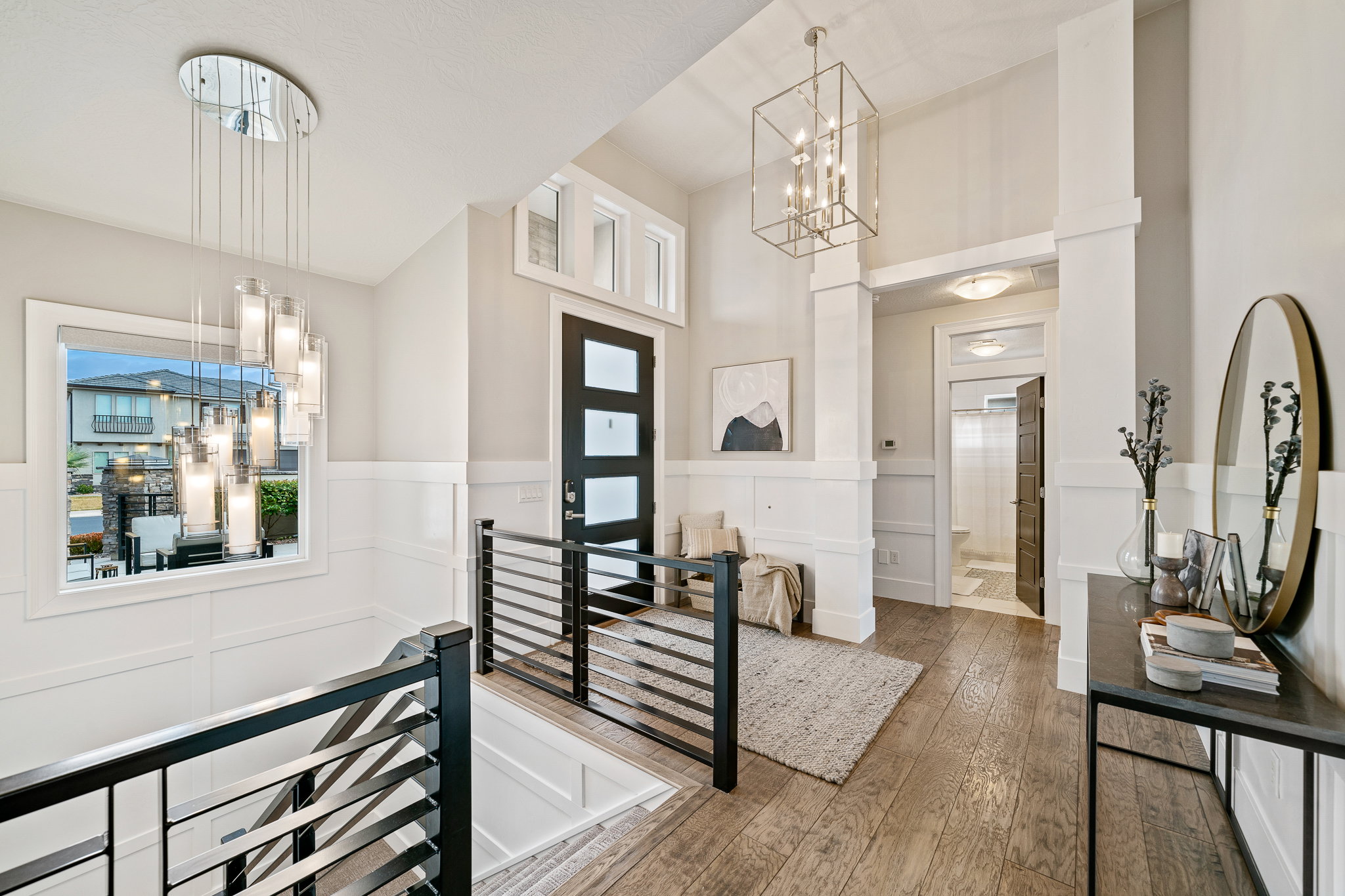 Foyer entrance with a decorative wall, wood-type flooring, a wainscoted wall, a chandelier, and a high ceiling