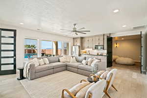 Living room featuring recessed lighting, light wood-style floors, a textured ceiling, and a ceiling fan