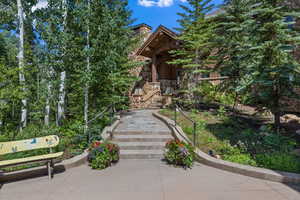 View of front of home featuring stairway, stone siding, and a porch