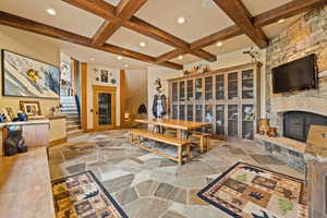 Living area with stone tile flooring, beamed ceiling, coffered ceiling, stairway, and a fireplace