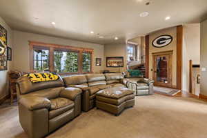 Carpeted living area with stairs and recessed lighting