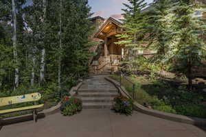 View of front of house featuring stairs, stone siding, and a porch