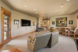 Living area featuring bar with sink, light colored carpet, and recessed lighting