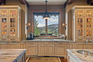Kitchen featuring pendant lighting, glass insert cabinets, and light stone counters