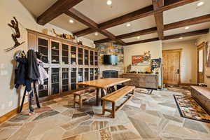 Dining room featuring beamed ceiling, light stone finish floors, recessed lighting, coffered ceiling, and a fireplace