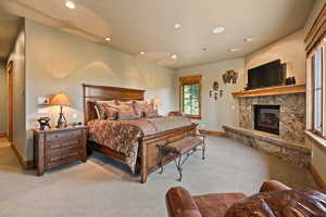 Bedroom featuring recessed lighting, a glass covered fireplace, and carpet floors
