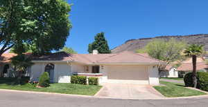 View of front of property featuring stucco siding, a garage, concrete driveway, a front lawn, and a chimney