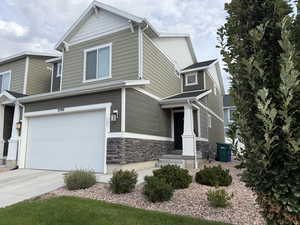 Craftsman-style house with stone siding, driveway, and a garage