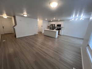 Unfurnished living room featuring dark wood finished floors, a textured ceiling, and track lighting