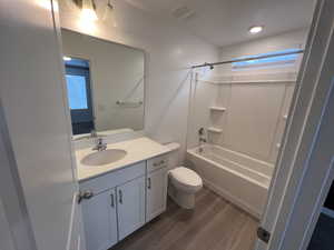 Bathroom with bathing tub / shower combination, vanity, and dark wood finished floors