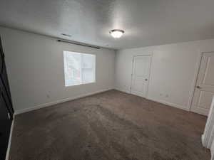 Unfurnished bedroom with a textured ceiling and dark colored carpet