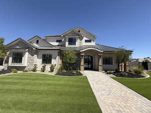 View of front of home featuring board and batten siding, a standing seam roof, a front lawn, and a metal roof