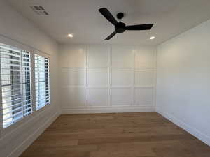 Empty room with a decorative wall, light wood finished floors, a ceiling fan, and recessed lighting