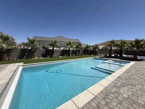 View of swimming pool with a fenced backyard, a pool with connected hot tub, and a patio