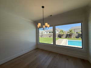 Unfurnished dining area featuring a chandelier, wooden walls, and wood finished floors