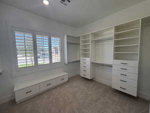 Spacious closet featuring dark colored carpet
