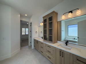 Bathroom with double vanity, a freestanding tub, and recessed lighting
