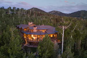 Back of property at dusk featuring stairway, a balcony, a chimney, a mountain view, and a metal roof
