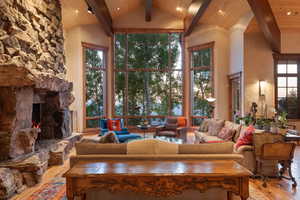 Living area with light wood finished floors, high vaulted ceiling, recessed lighting, healthy amount of natural light, and a fireplace