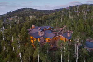 Aerial view of property's location featuring a forest and a mountainous background