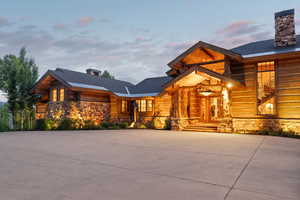 Log home featuring a chimney, stone siding, and a porch