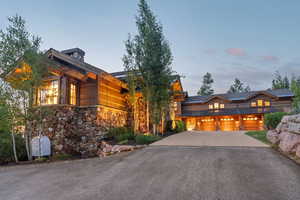 View of front of property featuring driveway, stone siding, and a garage
