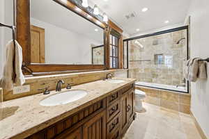 Bathroom with tiled shower / bath combo, double vanity, and recessed lighting