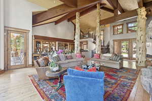 Living area with beam ceiling, high vaulted ceiling, hardwood / wood-style floors, and stairway