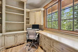Home office with light wood finished floors and built in desk