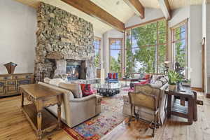 Living area featuring wood-type flooring, a wood ceiling with exposed beams, a fireplace, and high vaulted ceiling
