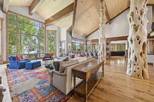 Living room with a wooden ceiling with exposed beams, high vaulted ceiling, and wood-type flooring
