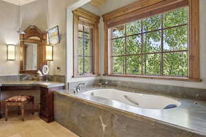 Full bath featuring vanity, a bath, and stone finish flooring