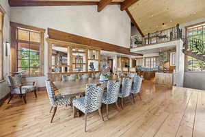 Dining space with beam ceiling, light wood finished floors, recessed lighting, stairs, and high vaulted ceiling