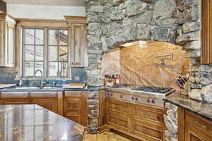 Kitchen featuring decorative backsplash, stainless steel gas stovetop, and brown cabinets