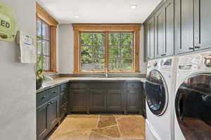 Washroom featuring cabinet space, independent washer and dryer, healthy amount of natural light, and light stone finish flooring