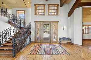 Foyer featuring hardwood / wood-style floors, a wood ceiling with exposed beams, stairs, and high vaulted ceiling