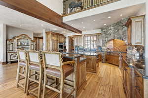 Kitchen with a center island, recessed lighting, light wood finished floors, brown cabinets, and dark stone counters