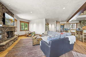 Living room with light wood-style flooring, a fireplace, recessed lighting, and beam ceiling